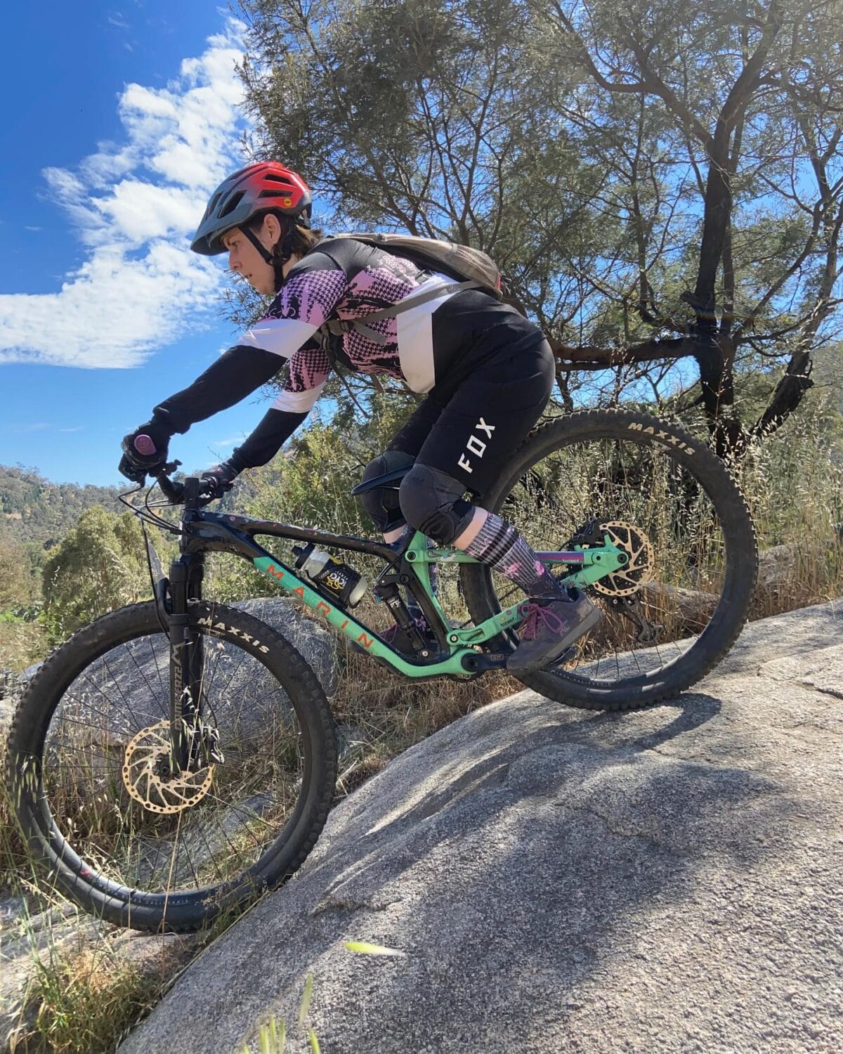 Mountain biker practicing rock roll skill during coaching session